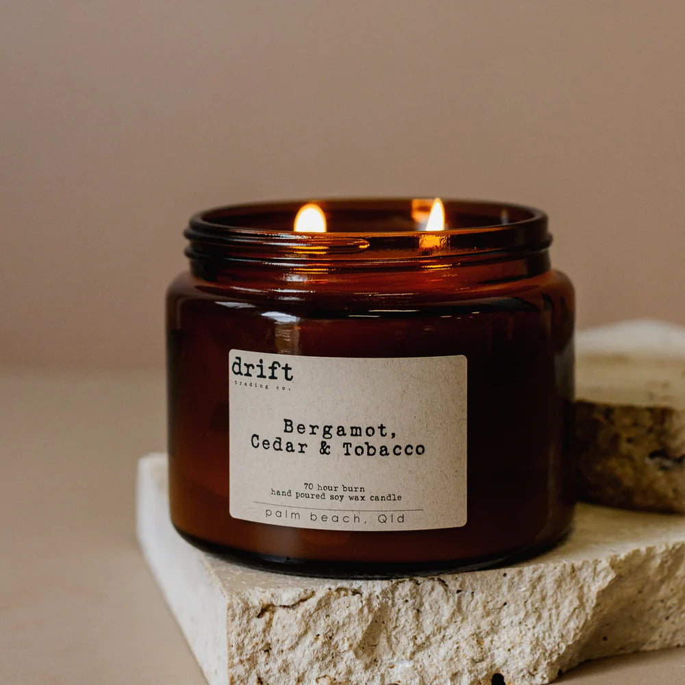 Drift Soy Candle with 'Bergamot, Cedar & Tobacco' on a stone surface.