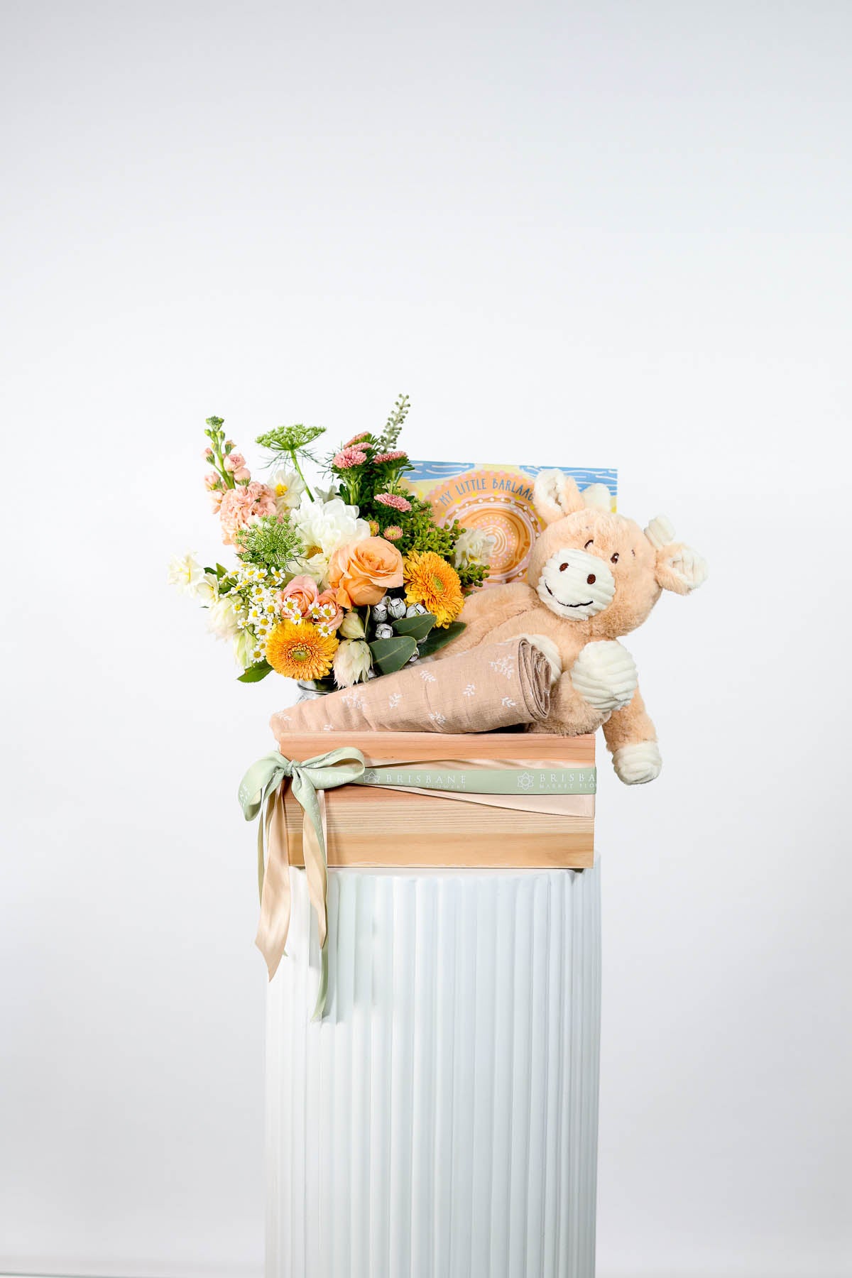 Floral arrangement with a soft plush toy in a decorative box on a white background