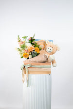 Floral arrangement with a soft plush toy in a decorative box on a white background