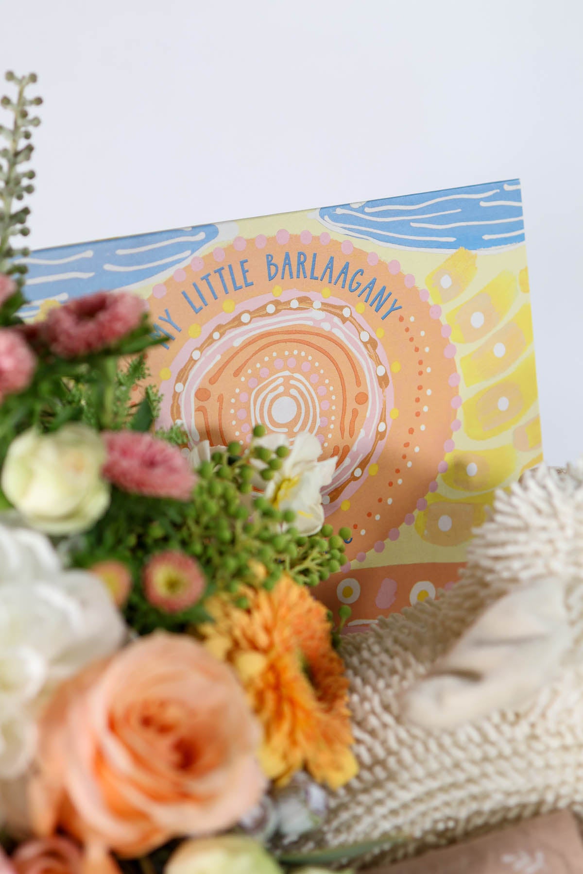 Floral arrangement with a 'Little Barlaagany' product packaging for baby.