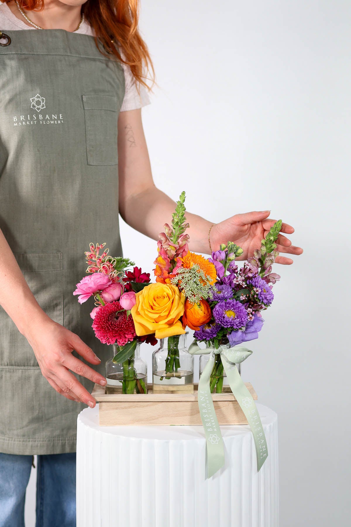 Person creating a colourful selection of flowers on a plinth.