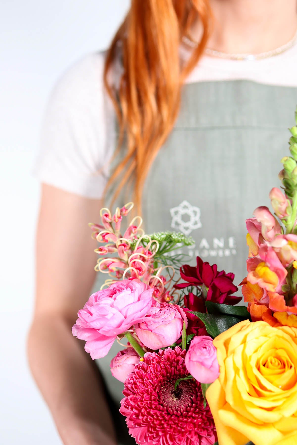 Person holding a selection of colourful flowers with a Brisbane Market flowers logo on an apron.