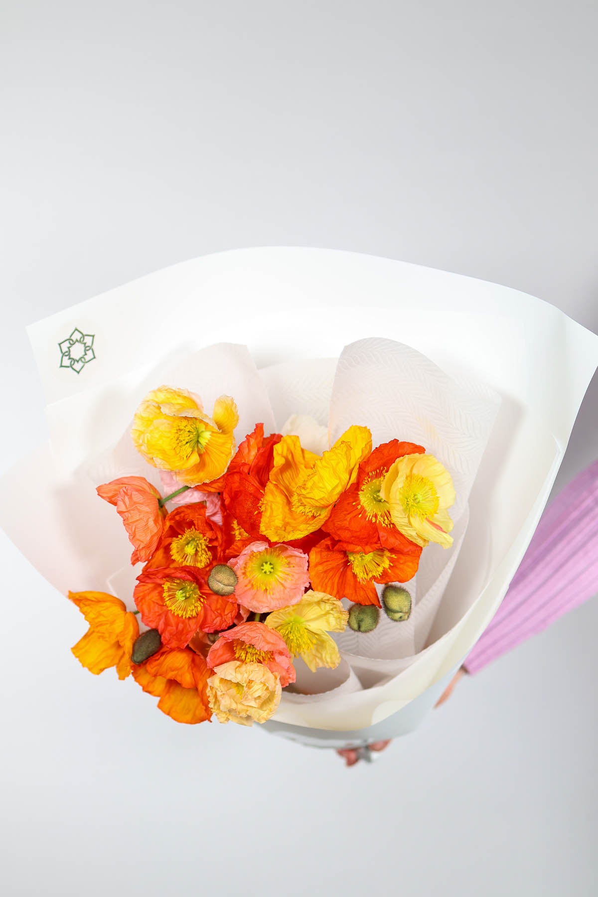 Market-style flower wrap with orange, pink & yellow seasonal flowers tied in white paper