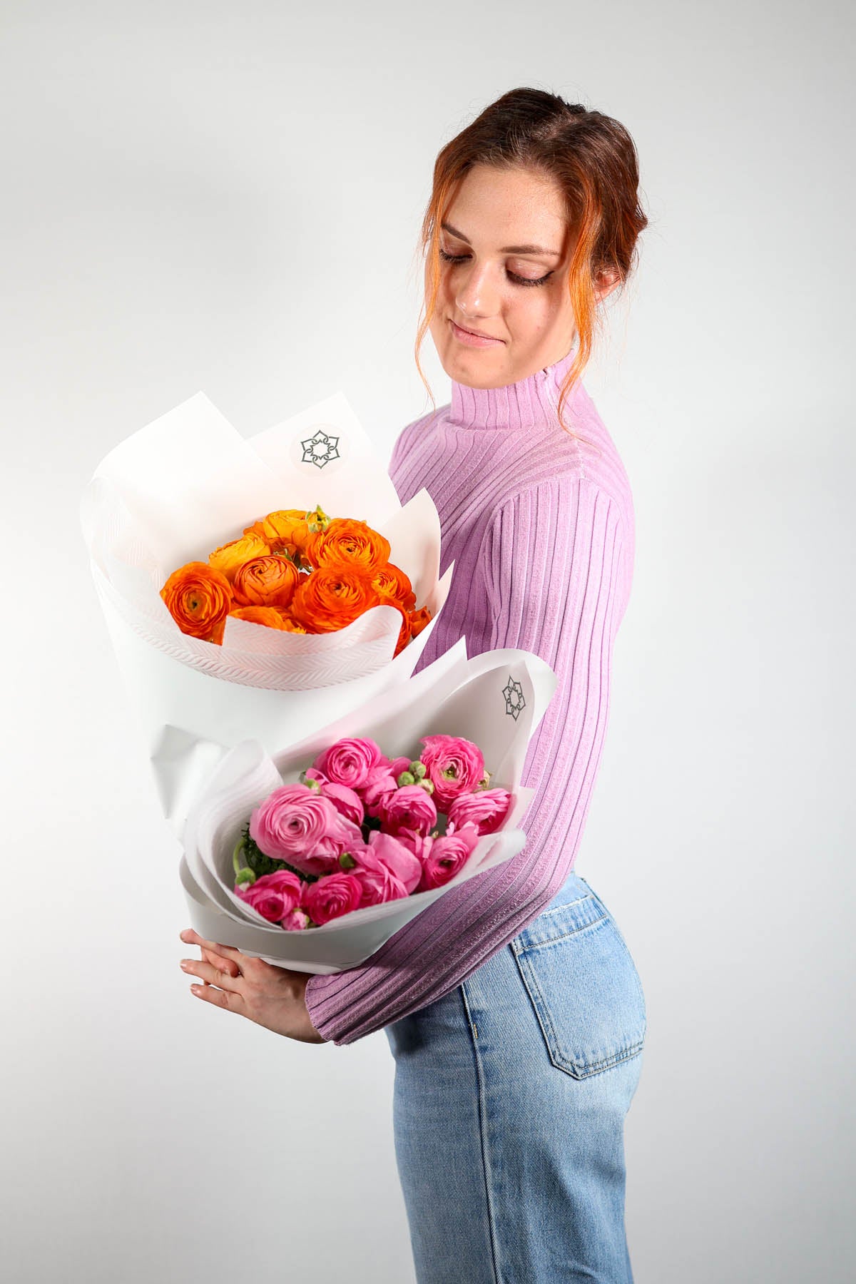 Woman holding a bouquet of ranunculas flowers with a plain background