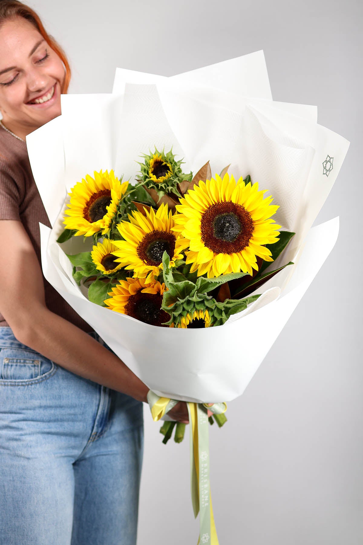 Person holding a bouquet of sunflowers against a plain background