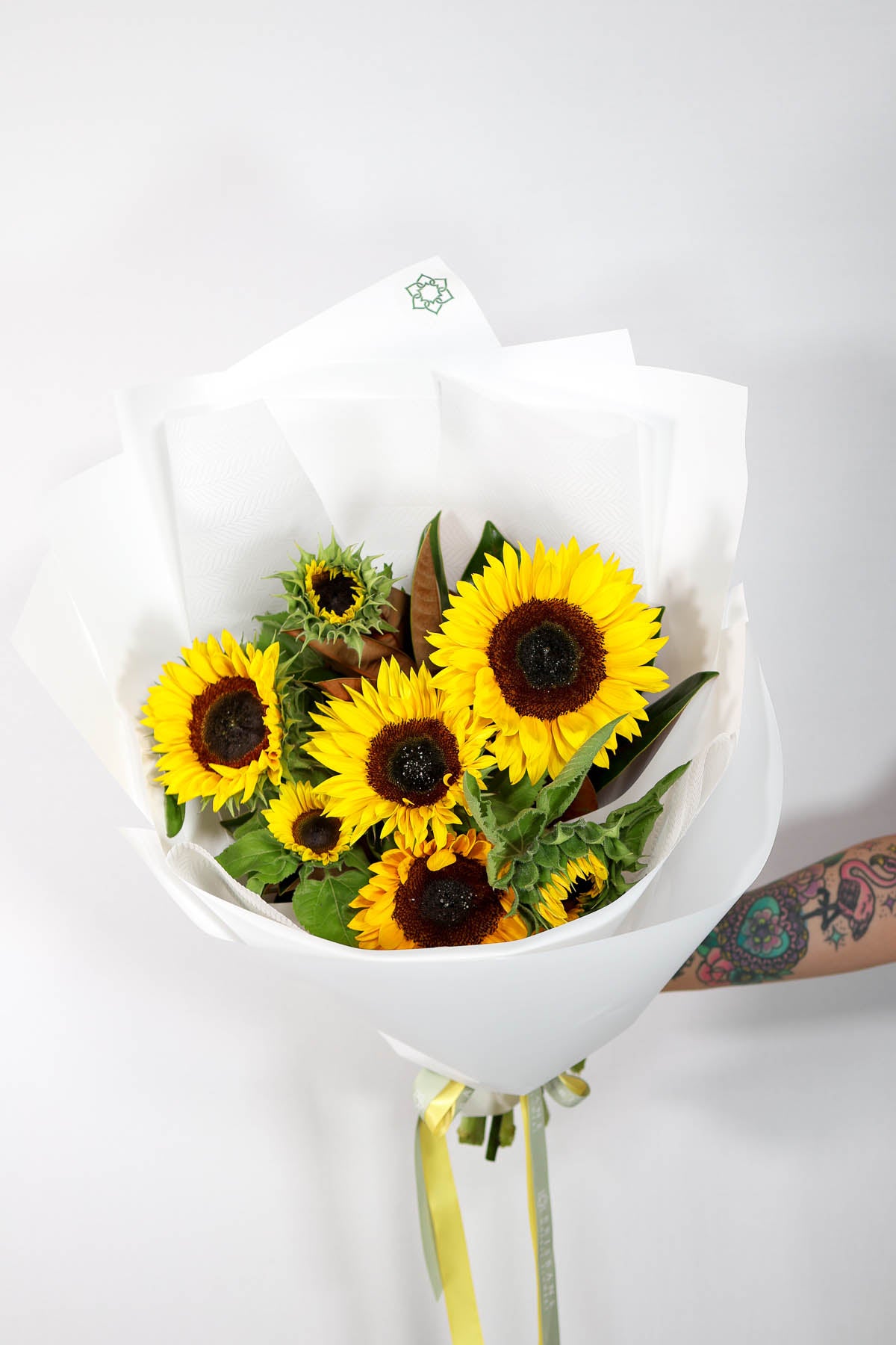 Bouquet of sunflowers in a white deluxe wrap on a light gray background