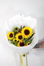 Bouquet of sunflowers in a white deluxe wrap on a light gray background