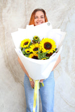 Person holding a bouquet of sunflowers smiling happily