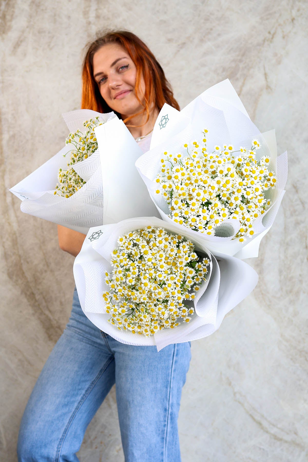 Woman holding bouquets of white and yellow tiny daisy flowers 