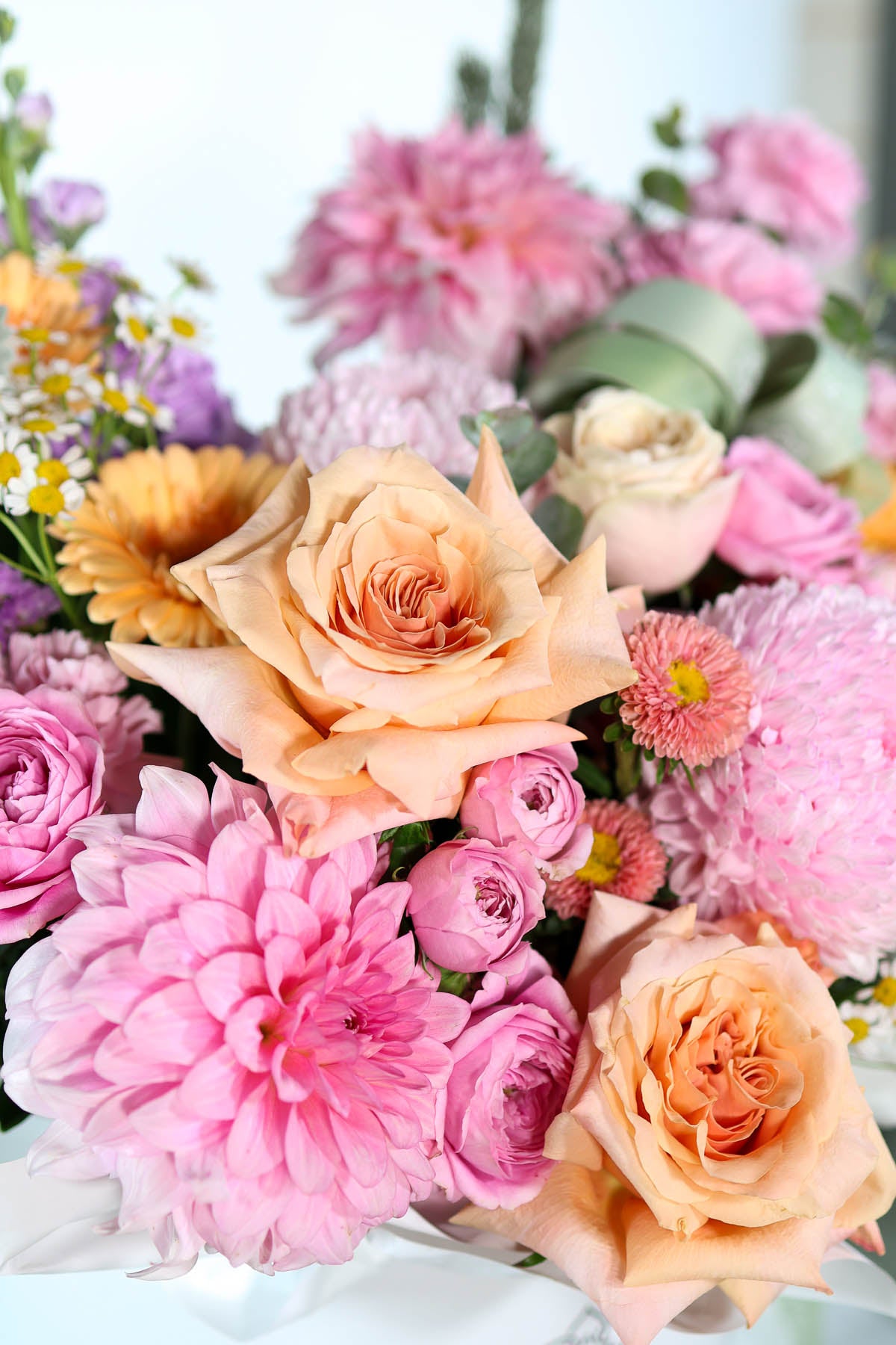 Pastel flowers including peach roses,  pink dahlia and daisies.