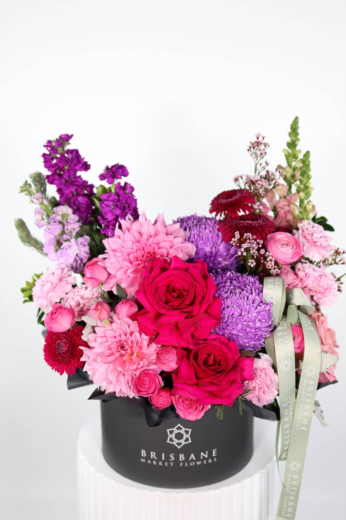 Colourful flower arrangement in a black box with 'Brisbane Market Flowers' branding on a white background.