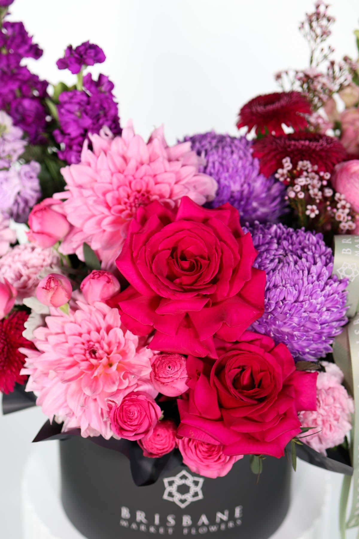 Black hatbox of hot pink and pale pink flowers in a Brisbane Market Flowers container.