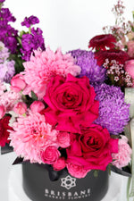 Black hatbox of hot pink and pale pink flowers in a Brisbane Market Flowers container.