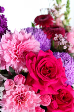 Bright pink and purple flowers including roses, dahlia and disbuds.