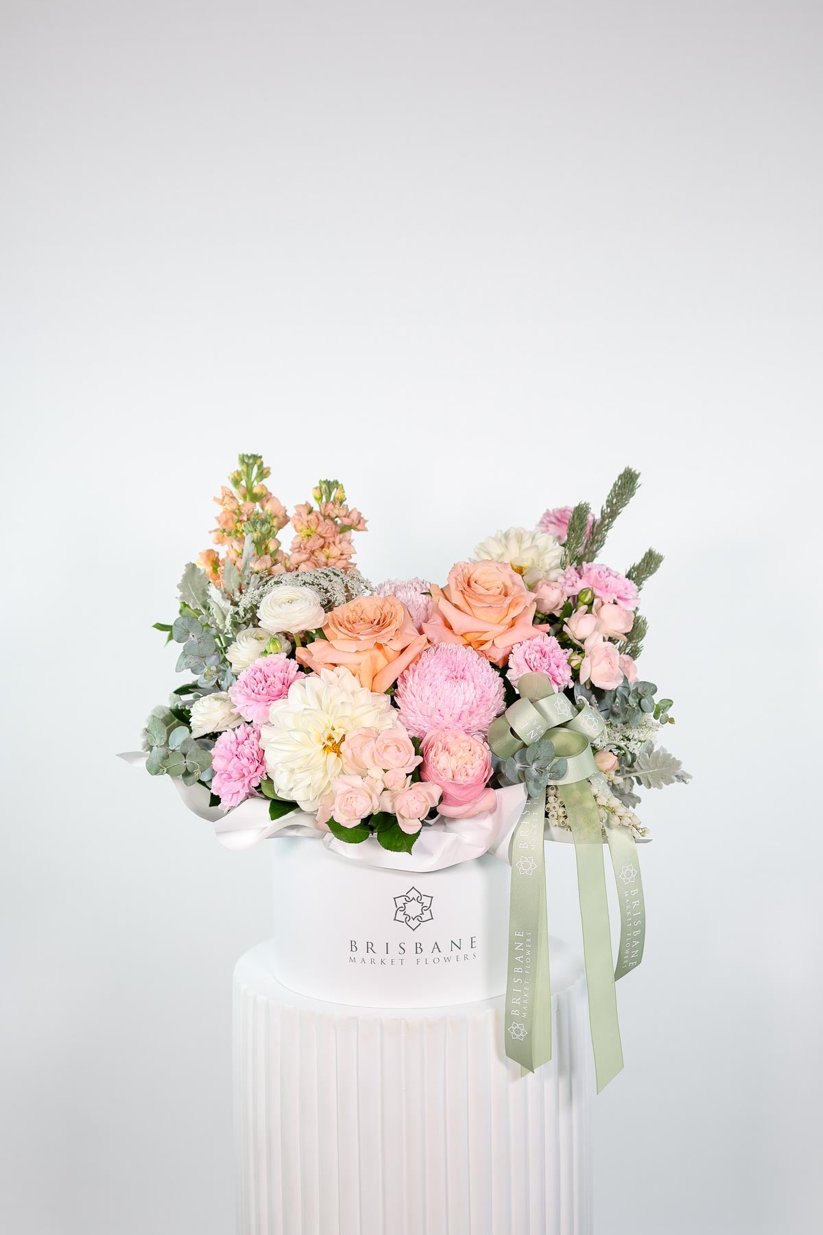 Front-facing Milan floral design in white hatbox with pink, peach, and ivory seasonal blooms and eucalyptus foliage