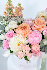 Close-up of Milan hatbox bouquet showing pale pink disbuds, white dahlias, and peach spray roses arranged in gentle dome shape
