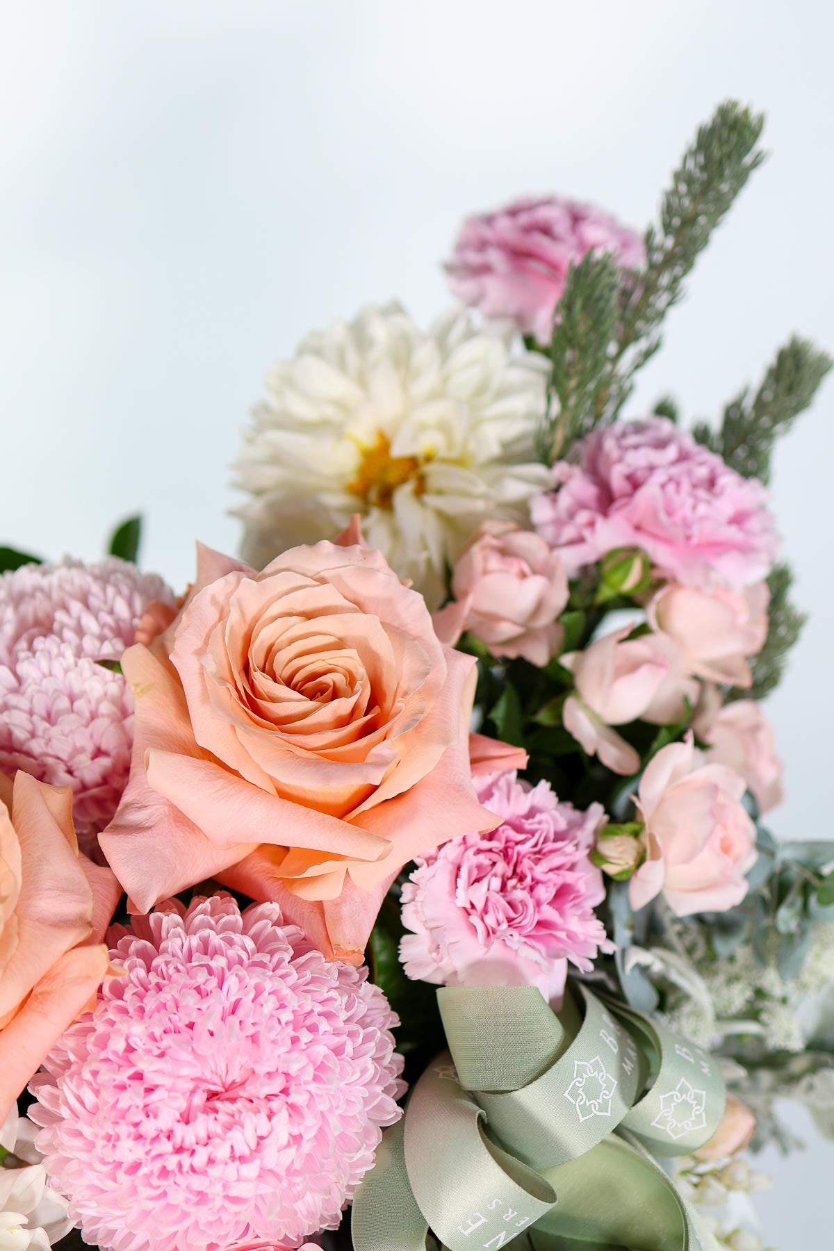 Top view of Milan hatbox bouquet with champagne tones, dusty miller leaves, and chiffon ribbon presentation