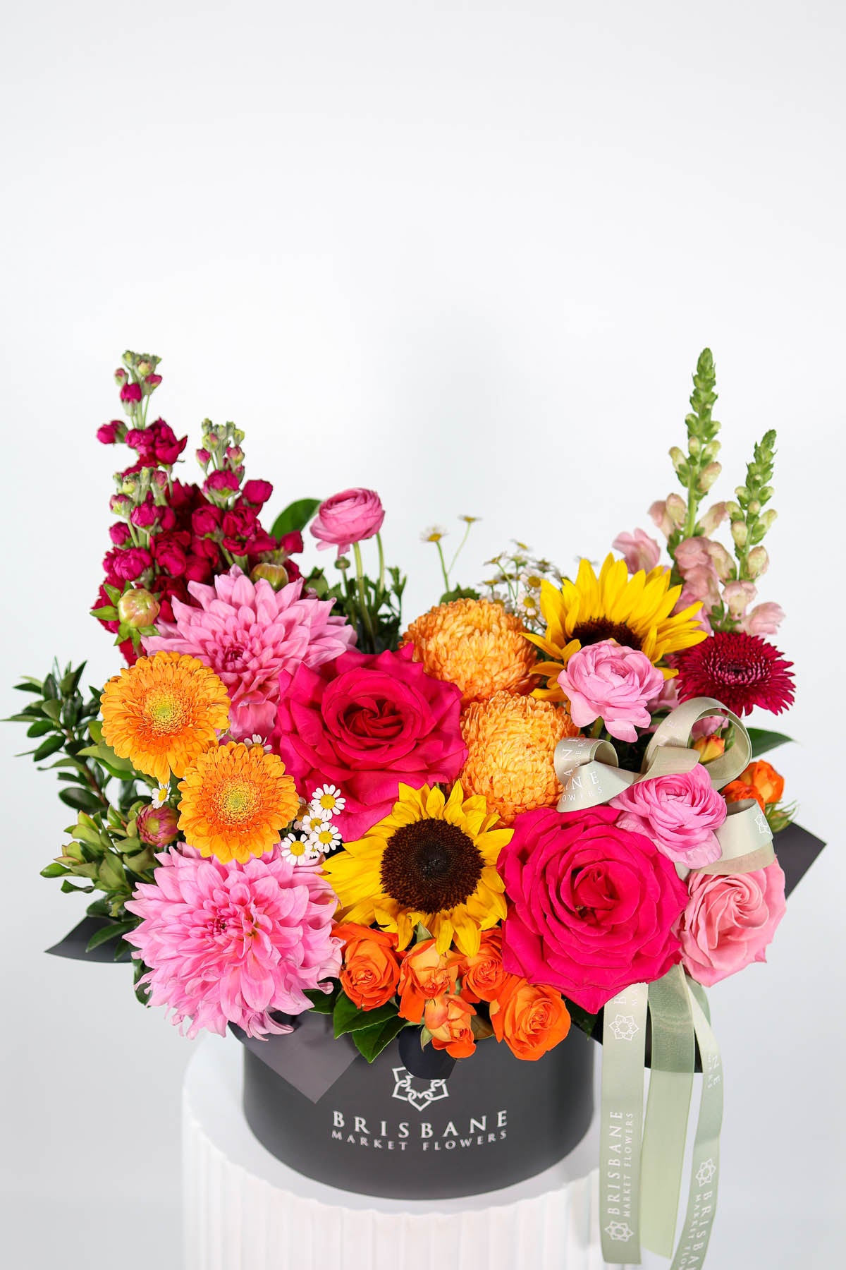 Colourful flower arrangement with sunflowers and pink and ornage flowers in a Brisbane Market Flowers box on a white background