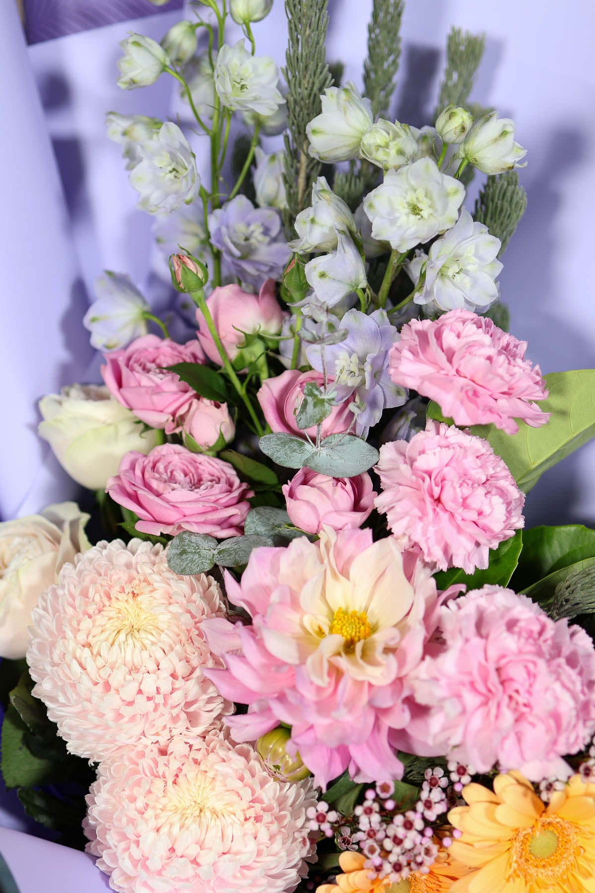 Close-up of pastel bouquet featuring roses and delicate seasonal florals with soft texture and tonal layering.