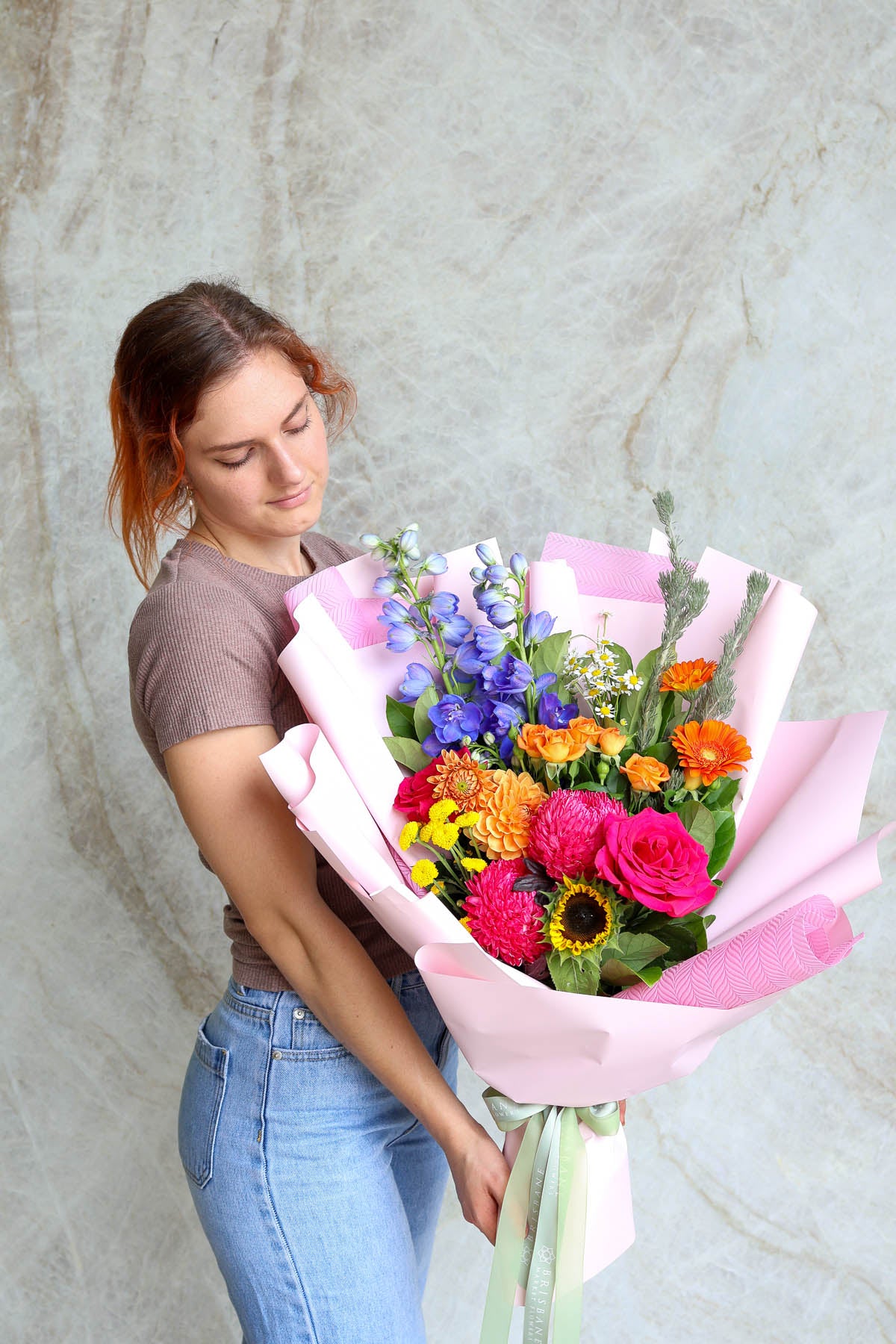 Bright congratulations bouquet wrapped in premium paper with structured front-facing presentation.