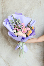 Graduation bouquet wrapped in soft lilac paper with signature ruffle styling, designed for gifting & photos.