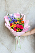 Bright graduation bouquet with vibrant seasonal flowers in a front-facing design, wrapped for gifting.