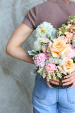 Vase arrangement showing pastel roses, dahlia, carnations & Queen Anne’s lace foliage, held behind someones back for size