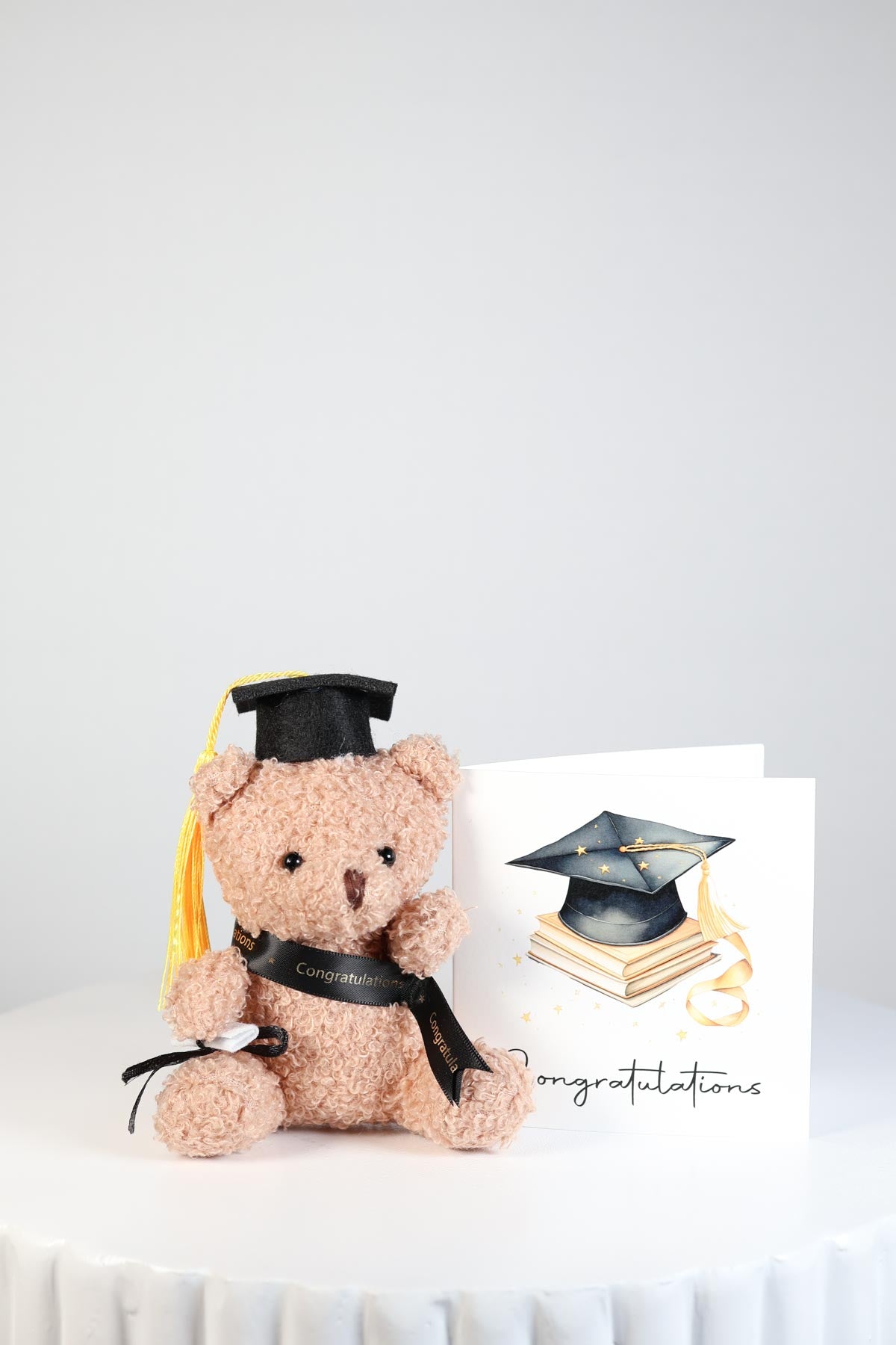 Graduation-themed teddy bear with cap and diploma and congratulations card.