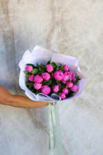 Bouquet of pink flowers held against a marble background