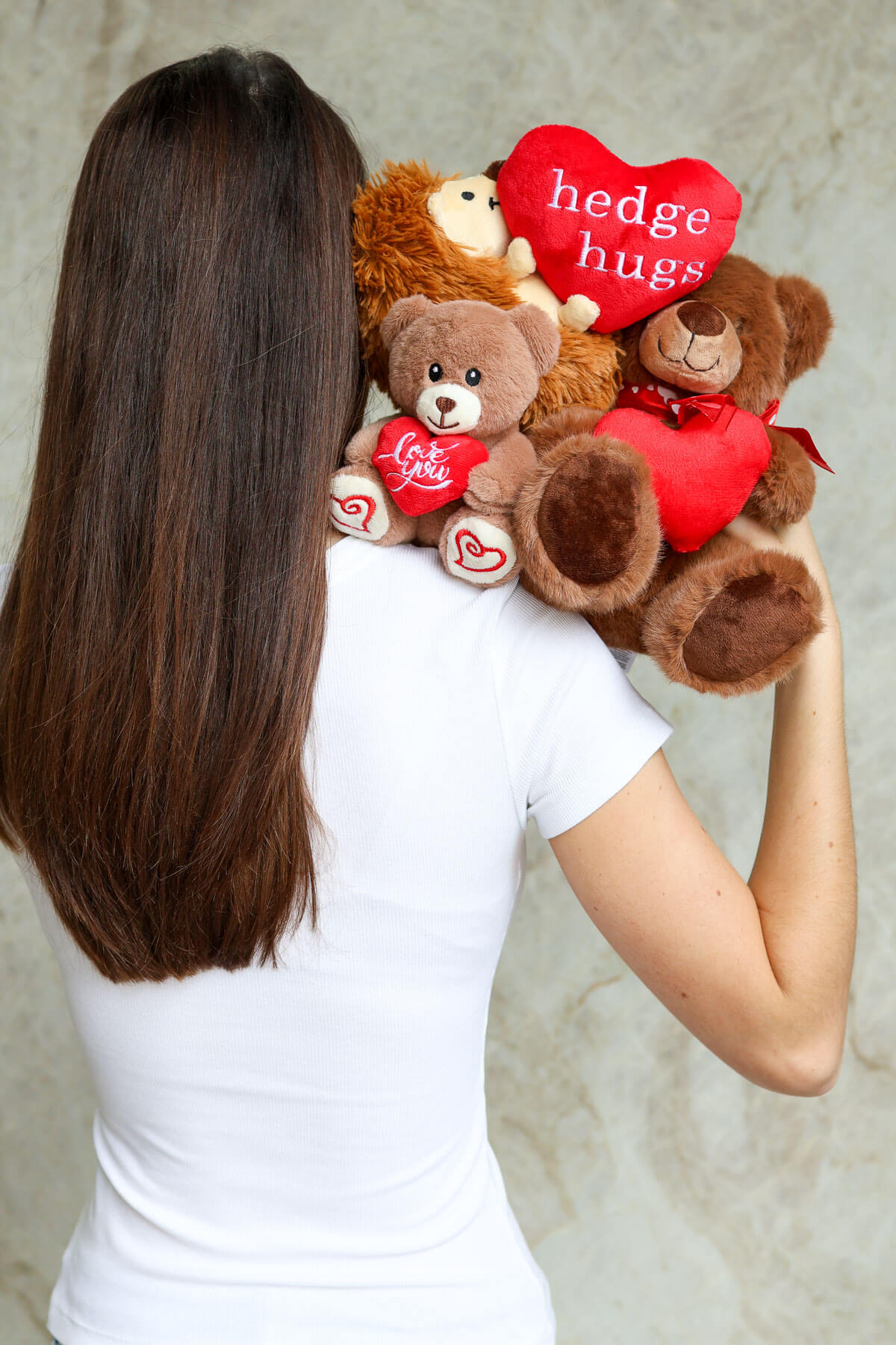 Person holding a bouquet of teddy bears with heart-shaped plush features 