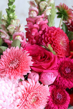 Pink gerberas, pink roses and red dahlias in a bouquet for delivery.