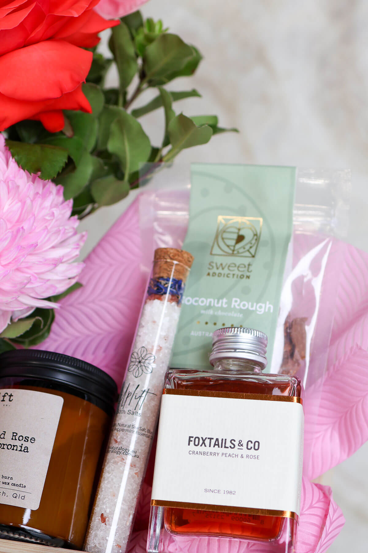 Assorted products including a cocktail tube of bath salts, and vase of pretty Valentine's flowers.