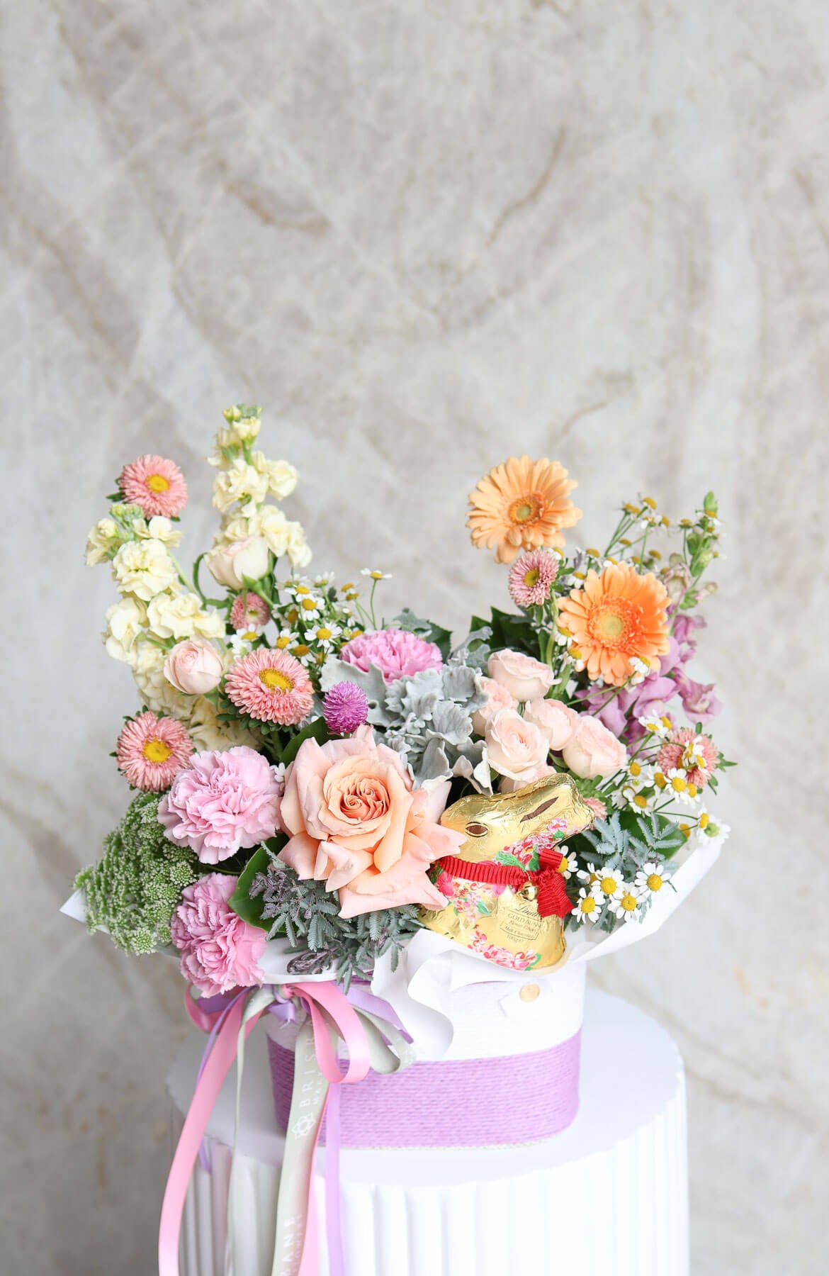 Easter flower basket in peach lemon pink and lilac tones with Lindt gold bunny