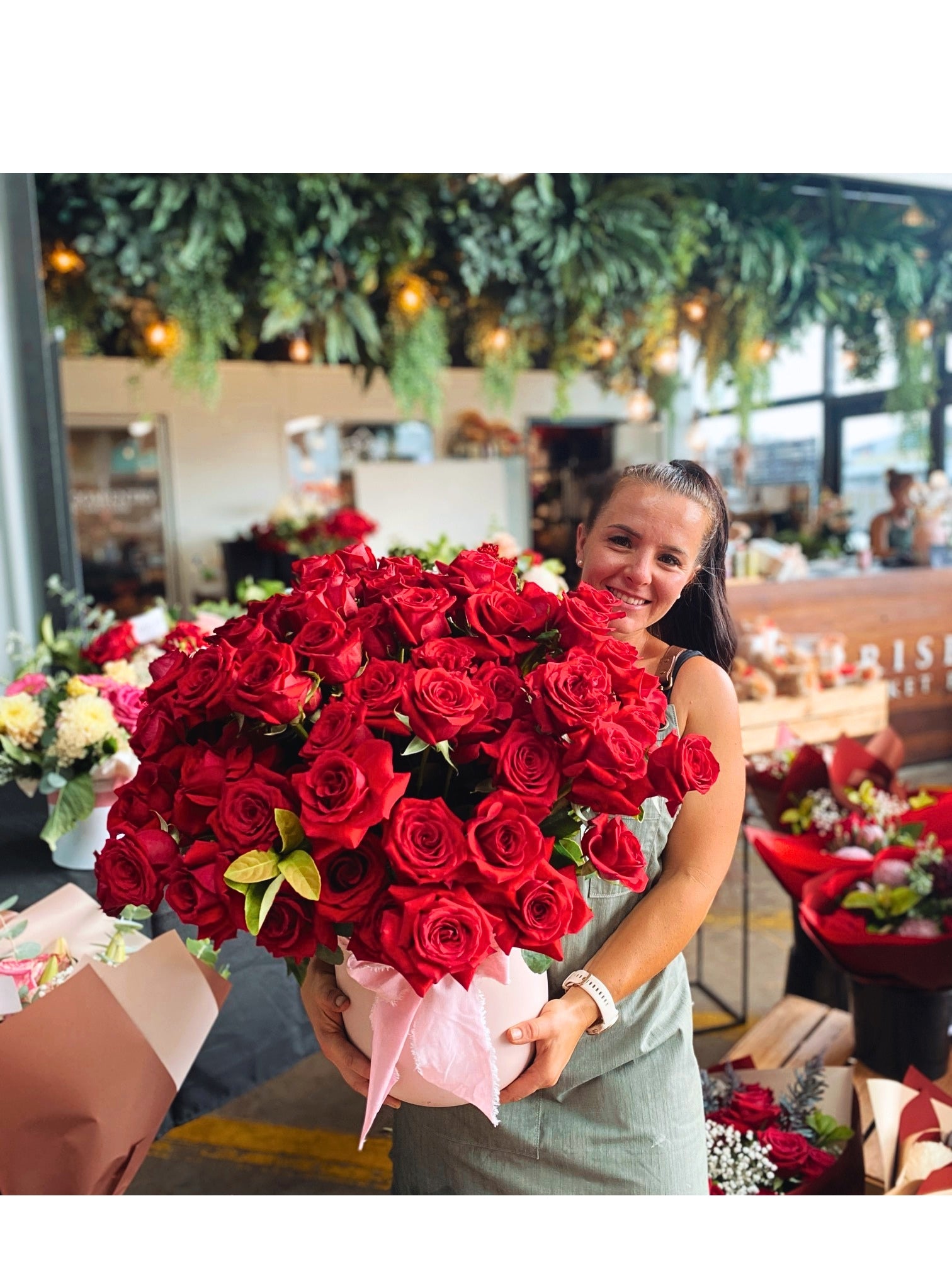 A woman holds a very large bouquet of red roses |Brisbane Market Flowers.