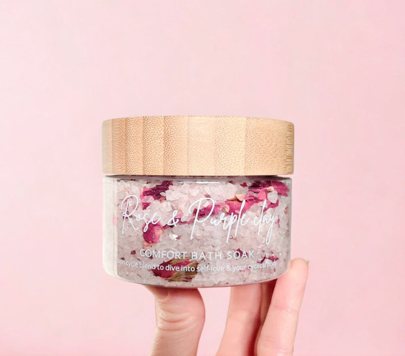 Rose & Purple Clay bath soak held by a hand against a pink background.