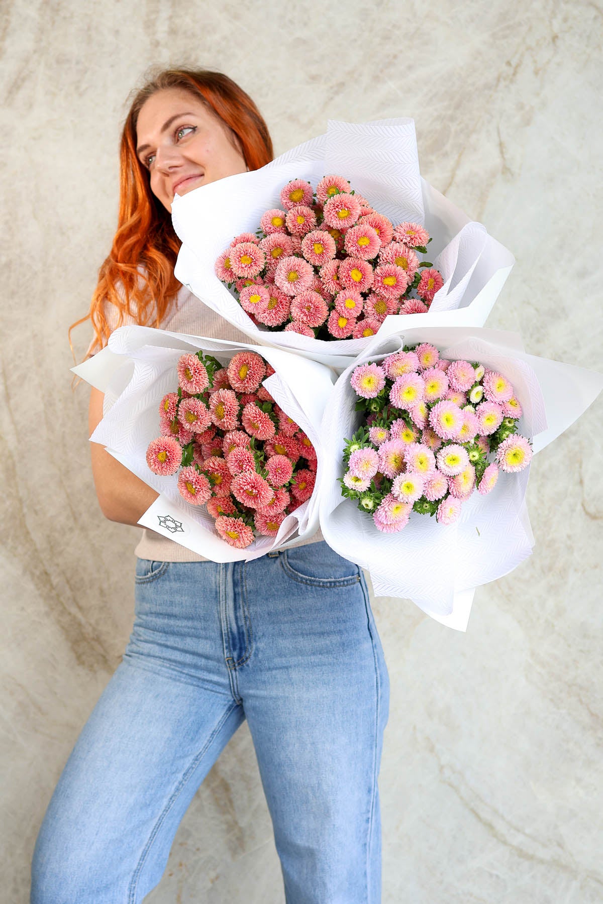 Woman holding bouquets of pink and yellow aster flowers 