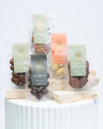 A selection of chocolate covered treats from Sweet Addiction, including almonds, coconut rough, honeycomb, speckles, freeze-dried strawberries, macadamias, displayed on a white surface.
