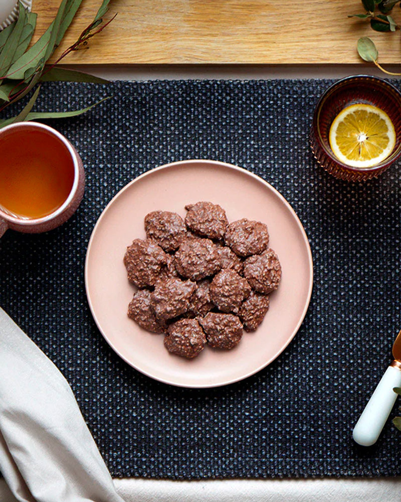 Coconut rough chocolates in a bowl with a table setting of tea and lemon drink.