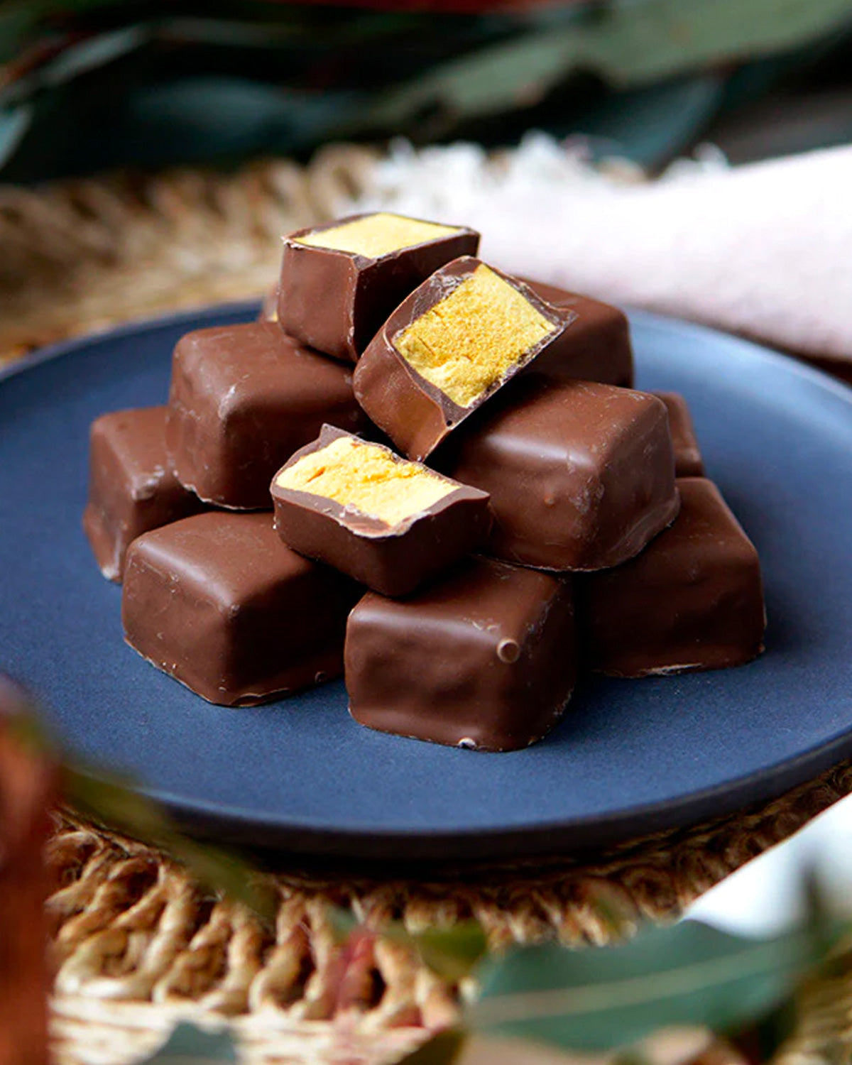 Honeycomb chocolates stacked up on a blue plate.