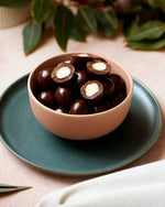 Chocolate covered almonds in a pink bowl.