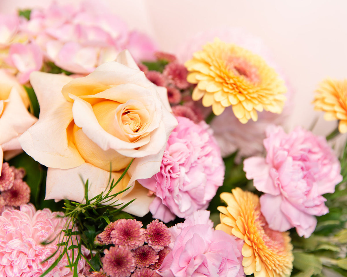 Close-up of a bouquet of flowers with yellow, pink, and green colors.