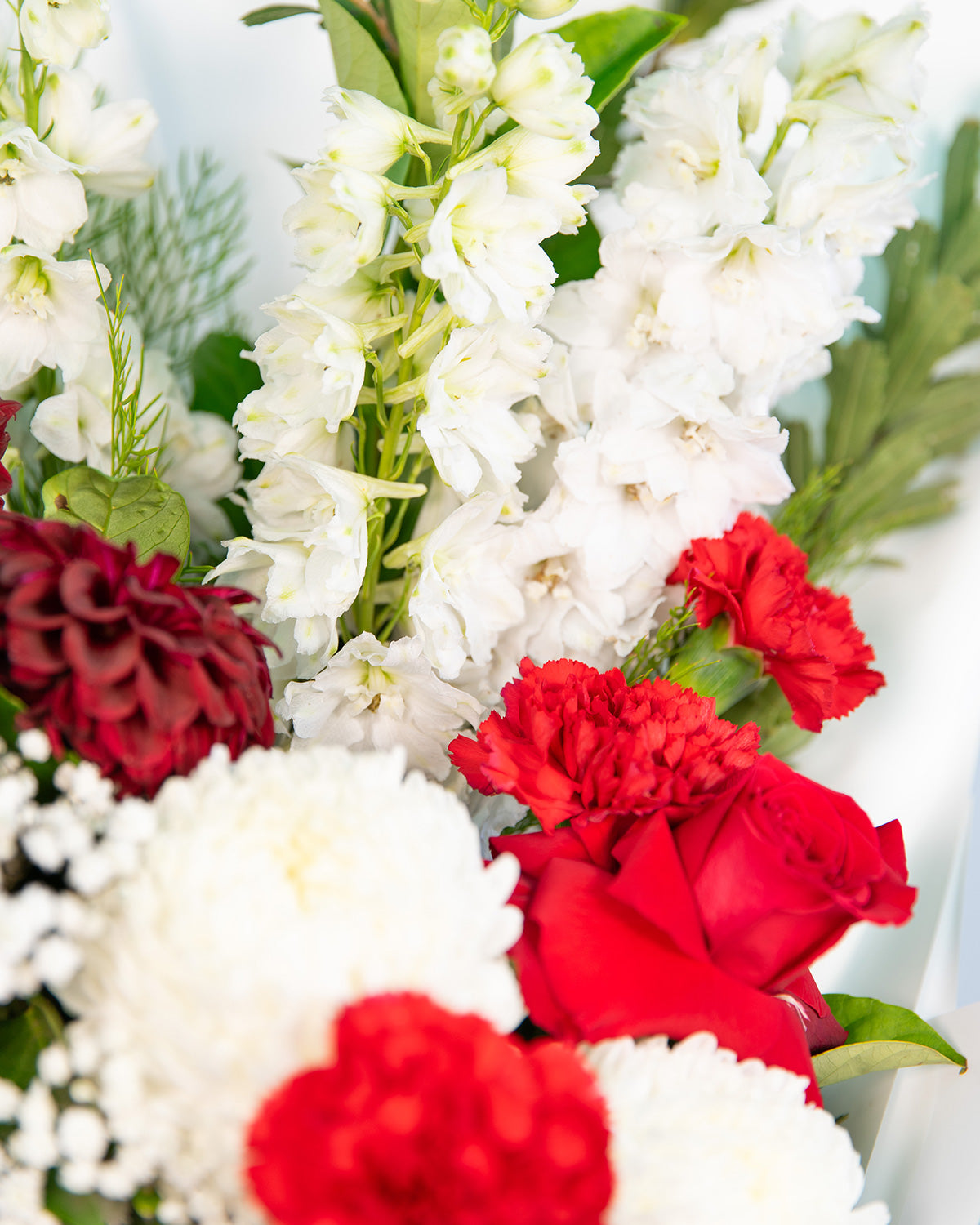 Elegant holiday flower bouquet with red roses, white stock, and seasonal greenery for same-day Brisbane delivery