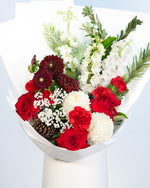 Holly Christmas bouquet featuring red roses, white blooms, and festive pine cones arranged by Brisbane Market Flowers
