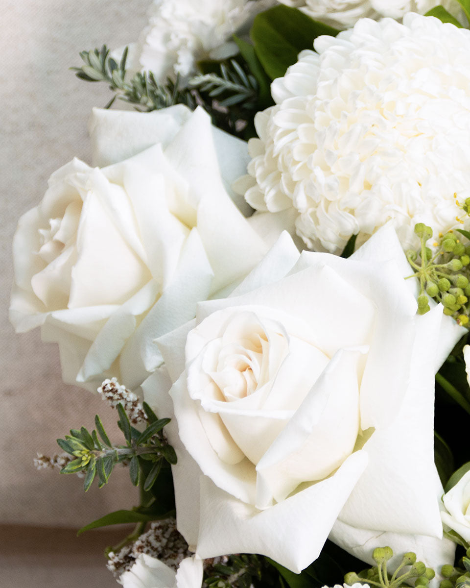 Close up of white roses in a handcrafted wreath and floral tribute. remembrance