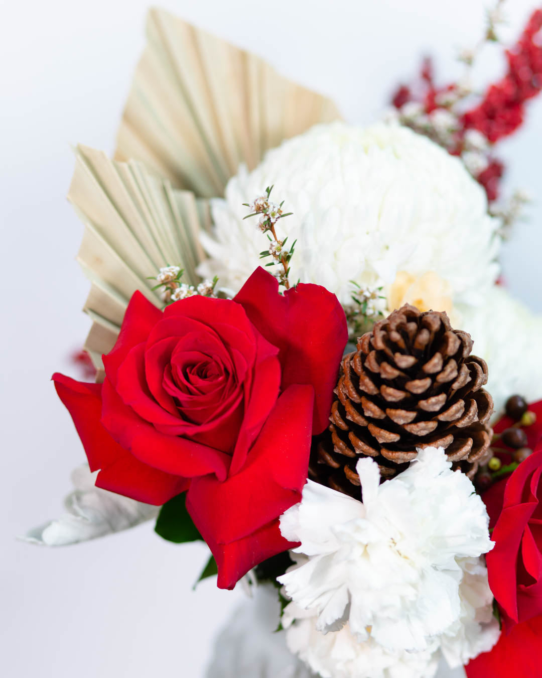 Close-up of Noelle vase arrangement showing roses, dried accents, and seasonal greenery