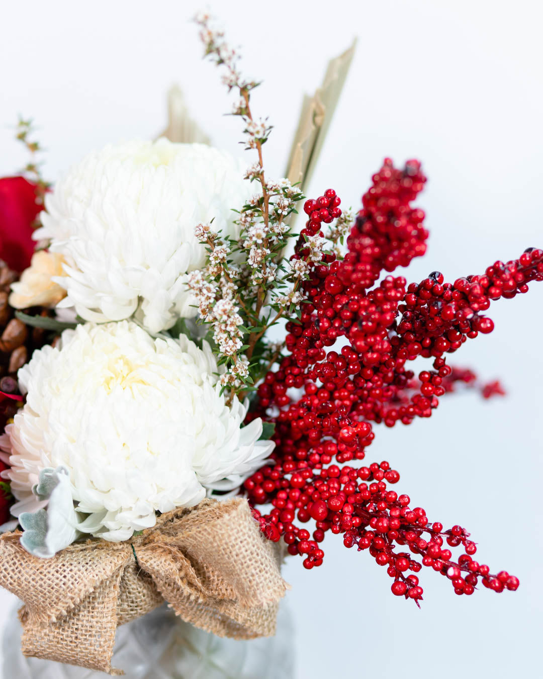Textured glass vase filled with holiday flowers in red, white, and green tones
